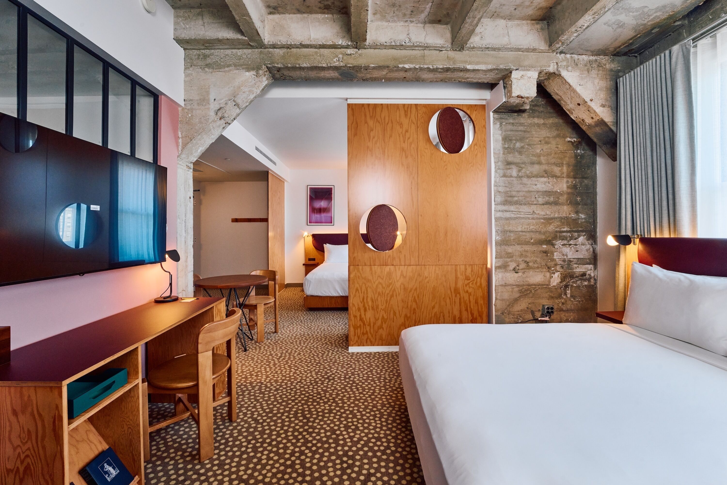Une chambre d’hôtel équipée d’un lit, d’un bureau, d’une chaise, d’une télévision et d’une armoire en bois.