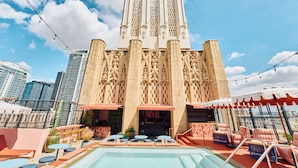 A rooftop pool area with a pool, lounge chairs, and a view of a historic building with intricate architecture.