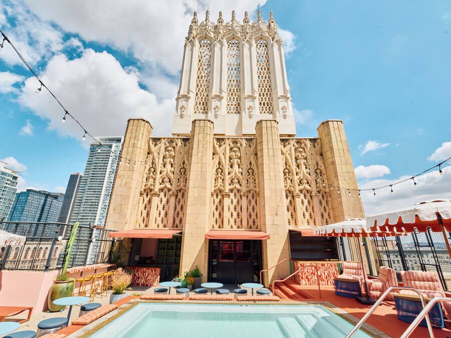 A rooftop pool area with a pool, lounge chairs, and a view of a historic building with intricate architecture.