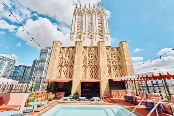 A rooftop pool area with a pool, lounge chairs, and a view of a historic building with intricate architecture.