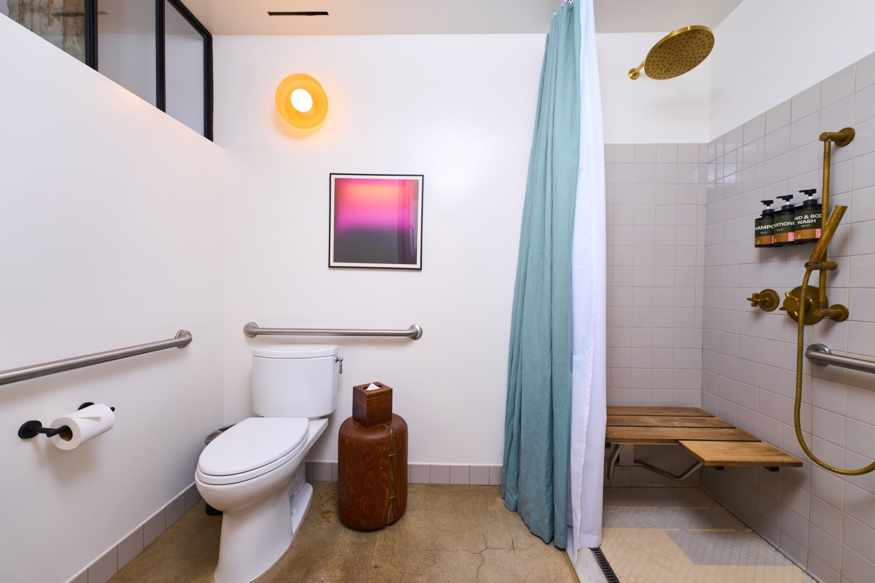 A modern bathroom with a toilet, bidet, shower, and a framed picture on the wall.