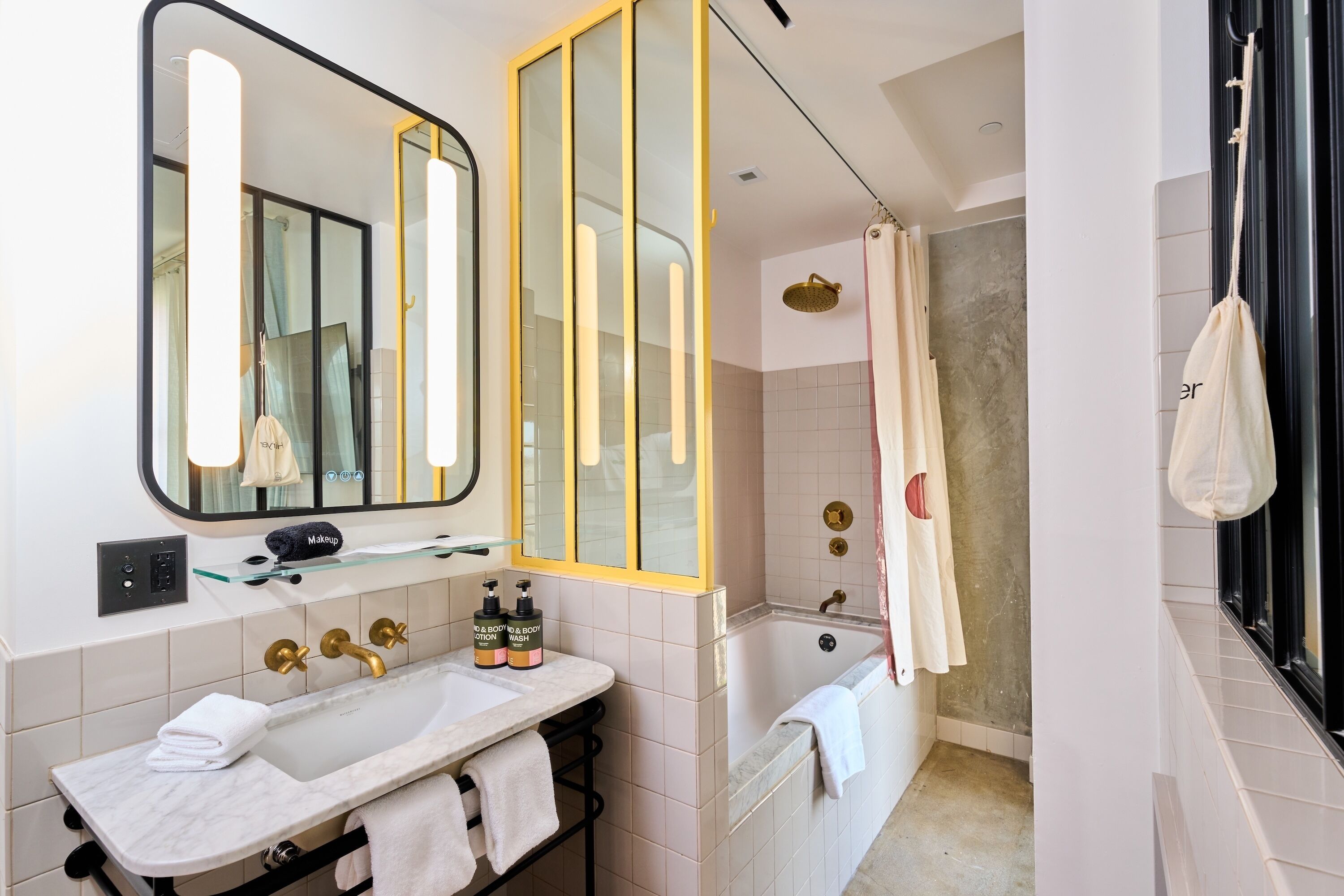 A modern bathroom with a large mirror, a bathtub, a shower area, and a vanity with a sink and towel rack.