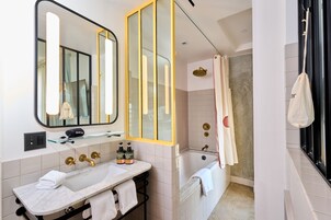 Un bagno moderno con un ampio specchio, una vasca da bagno, un box doccia e un mobile lavabo con lavandino e porta asciugamani.