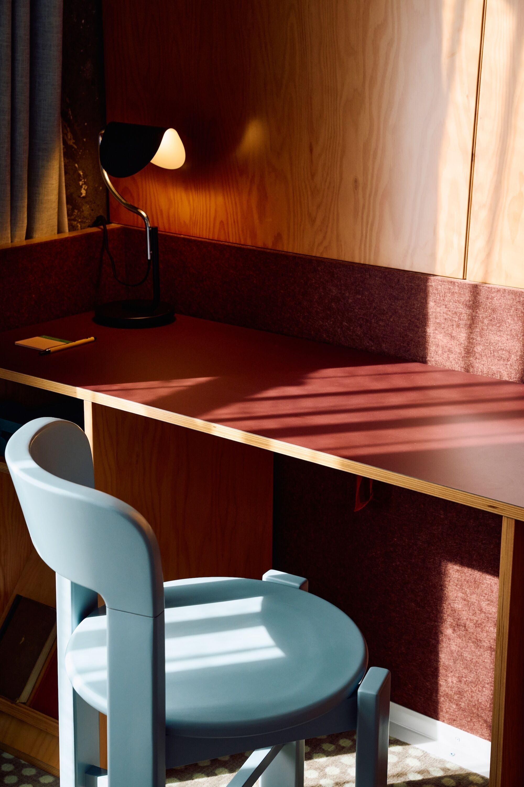 Una habitación con escritorio, silla, lámpara y ventana.
