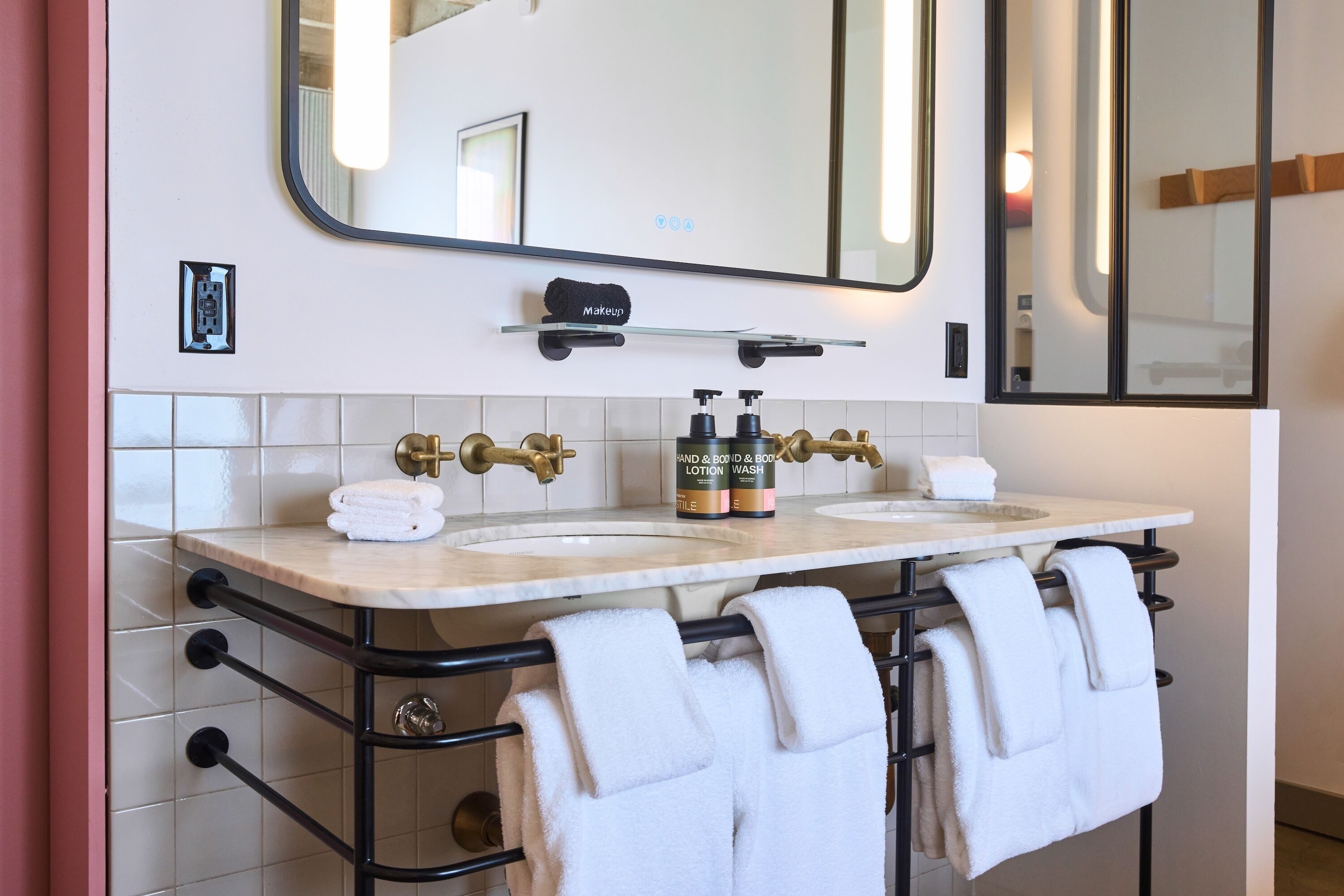 Un bagno con due lavandini, uno specchio grande e un portasciugamani con diversi asciugamani.