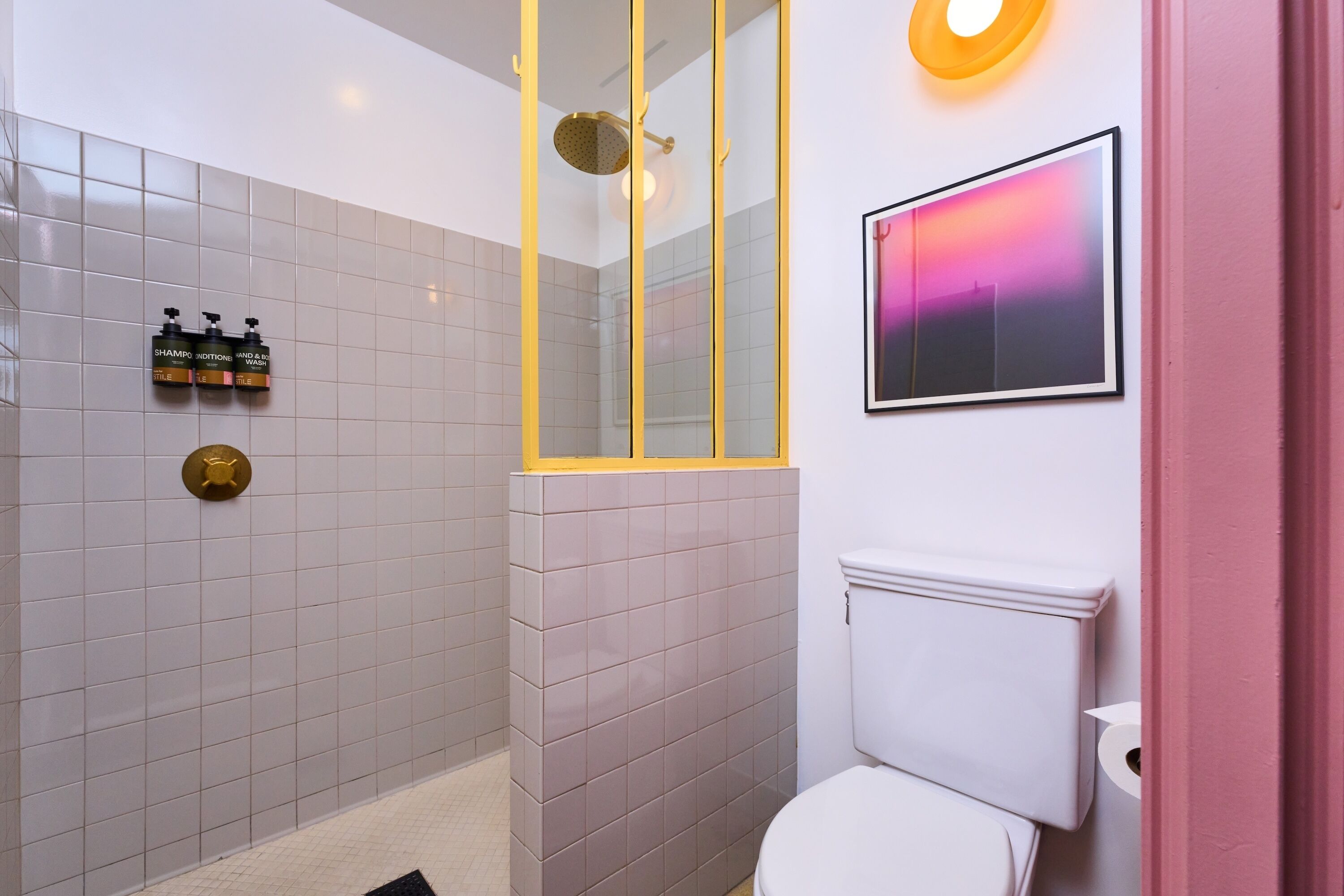 A bathroom with a shower, toilet, and a framed picture on the wall.