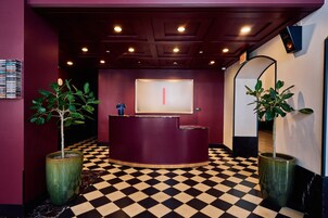 A reception area with a checkered floor, a reception desk, and potted plants.