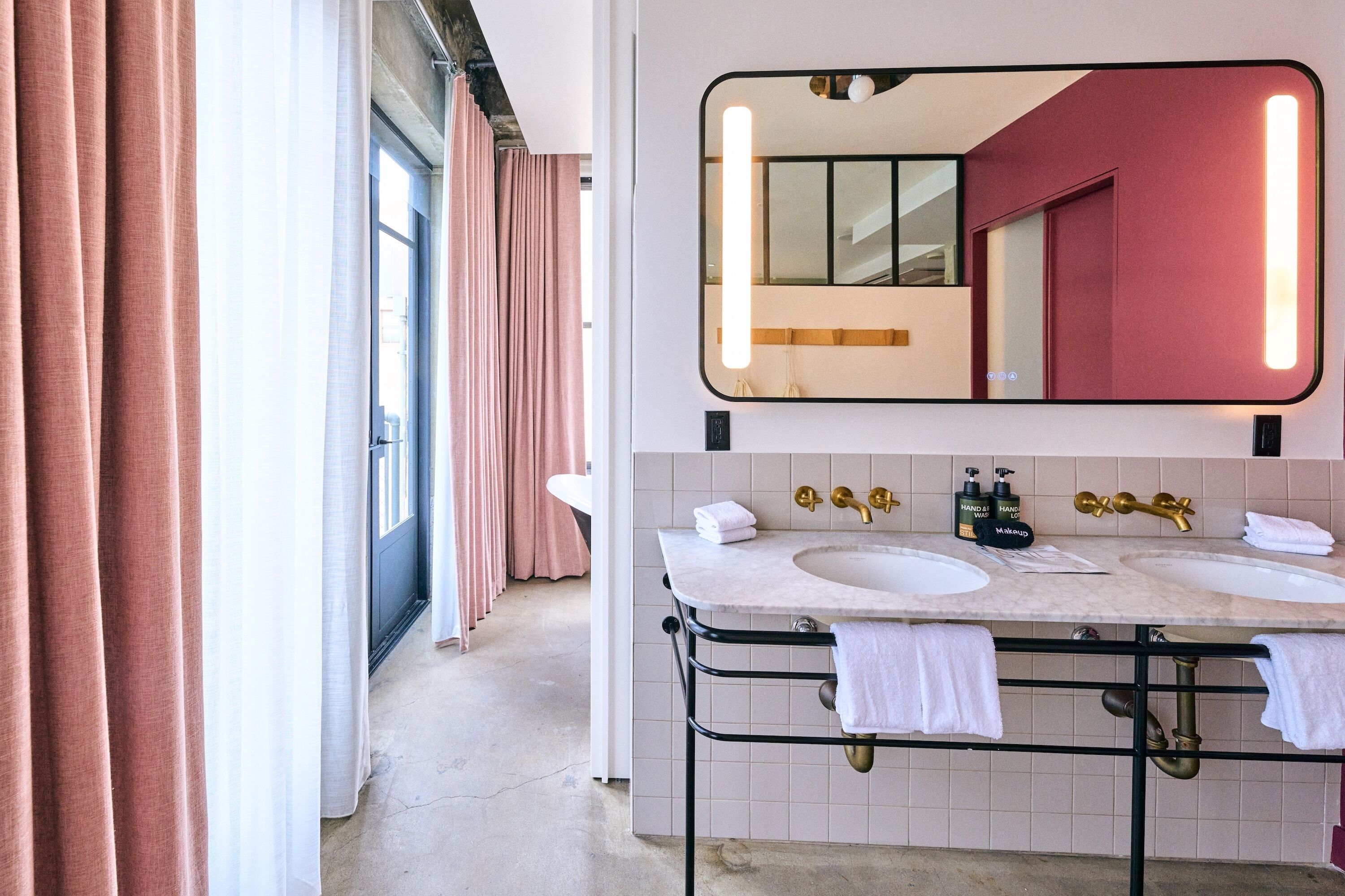 A bathroom with two sinks, a large mirror, and a view of a hallway.