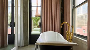 Un baño con bañera, ventana con cortinas y vistas al exterior.