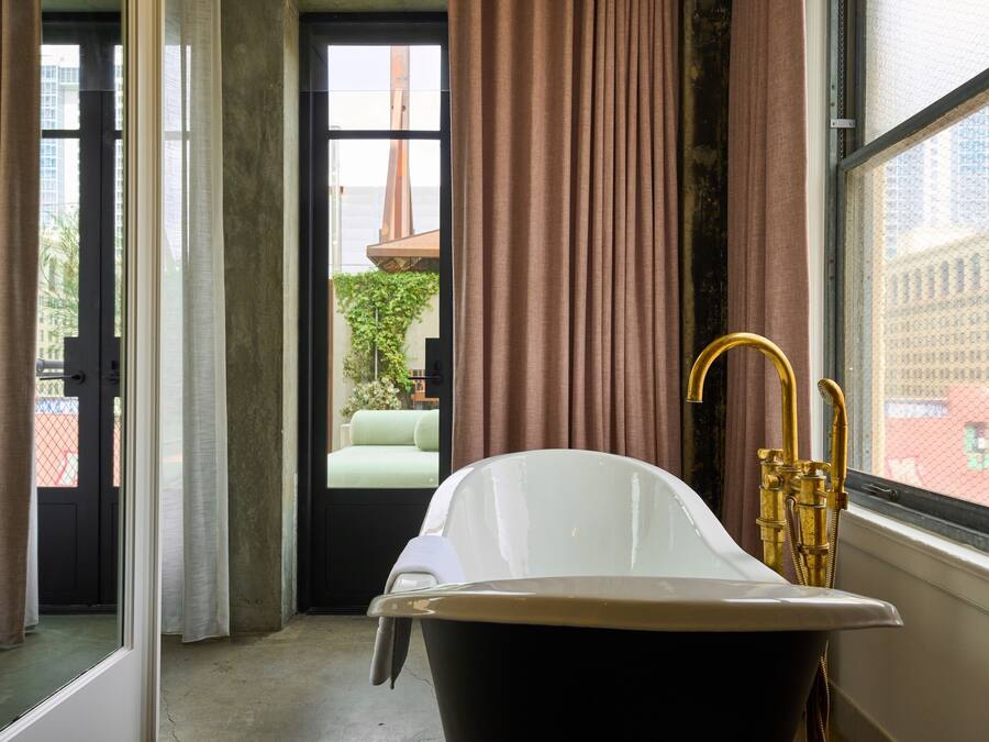 Un baño con bañera, ventana con cortinas y vistas al exterior.