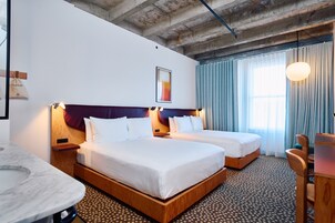 A hotel room with two beds, a wooden headboard, a marble table, and a patterned carpet.