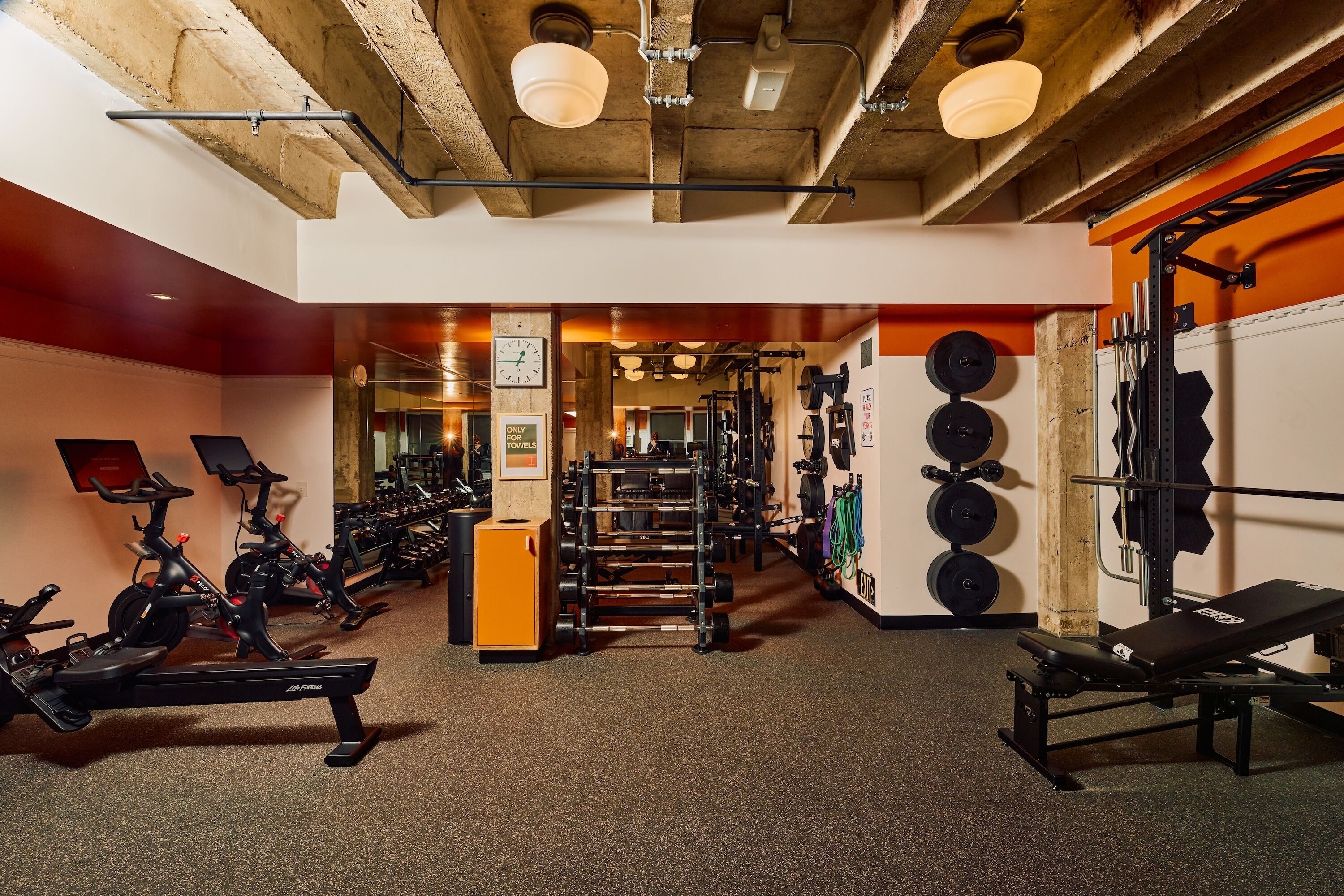A gym with exercise equipment, a weight rack, and a bench.