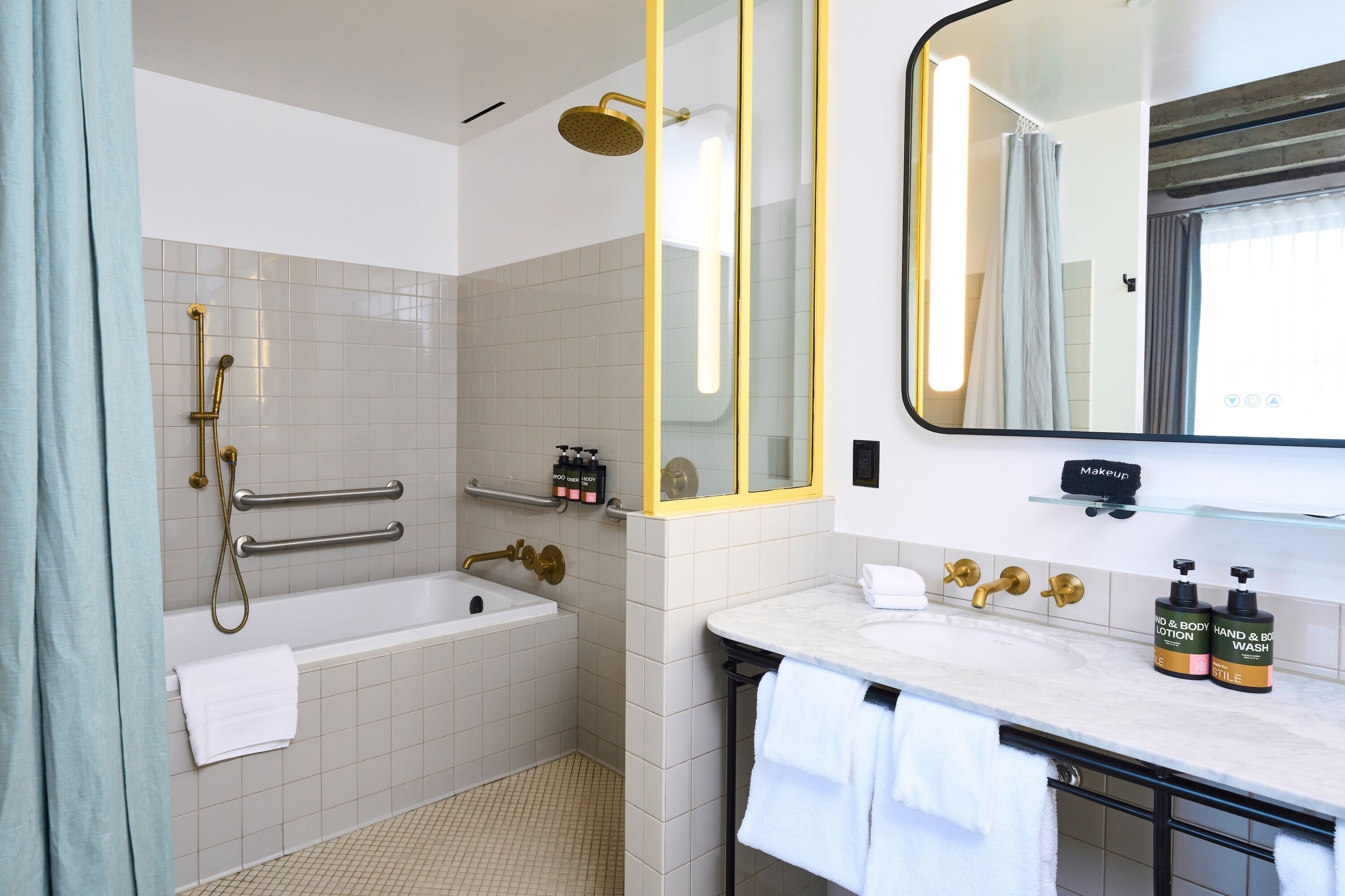 A modern bathroom with a bathtub, shower, vanity, and a large mirror.