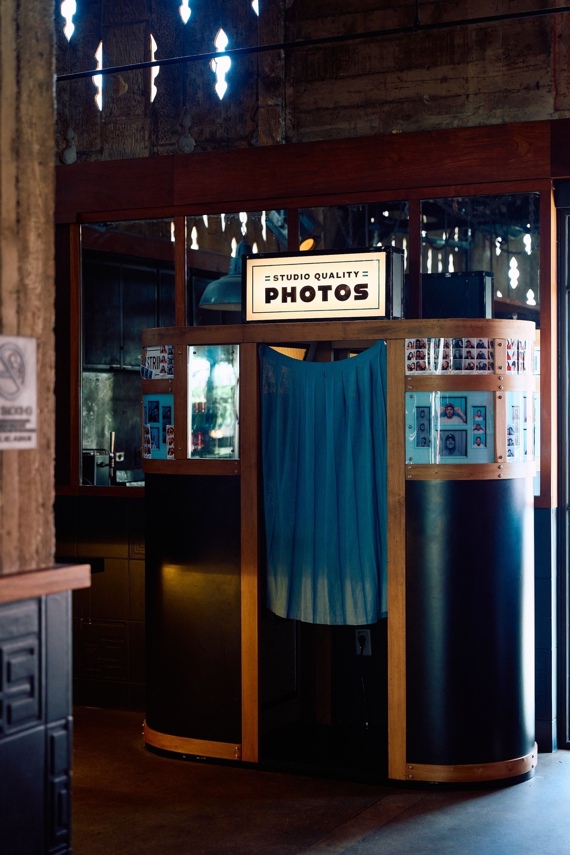 Una cabina fotografica con un cartello che riporta la scritta 'STUDIO QUALITY PHOTOS' e una tenda blu.