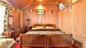 A wooden room with a bed, a dresser, a mirror, and a framed picture on the wall. - Houseboat Zaindari Palace (Srinagar)