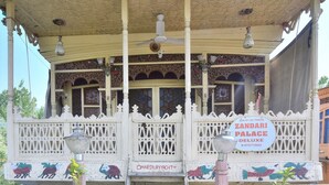 A Zandari Palace Deluxe with ornate white lattice railings, a ceiling fan, and decorative lighting. - Houseboat Zaindari Palace (Srinagar)