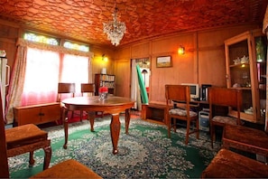 Quarto com teto de madeira, um candelabro, uma mesa redonda e várias cadeiras.