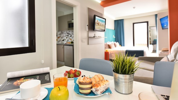 A hotel room with a dining table set with breakfast, a laptop, and a potted plant. - Hotel Apartamentos Bajamar (Las Palmas de Gran Canaria)