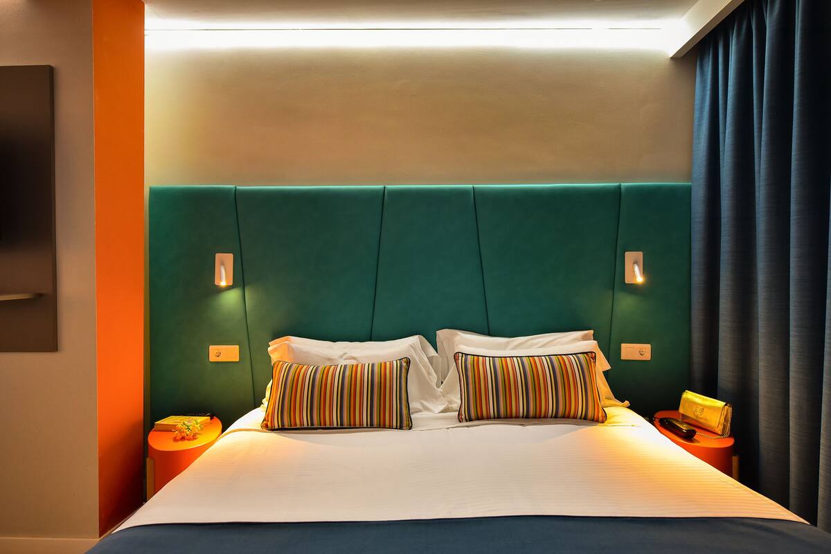 Ein Hotelzimmer mit einem großen Bett, einem grünen Kopfteil und zwei Nachttischen mit Lampen.