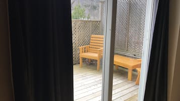 Una terraza de madera con un banco y una mesa, delimitada por un cerramiento de celosía.