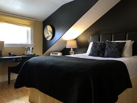 Una habitación de hotel moderna con una cama, mesita de noche, lámpara y un reloj en la pared.
