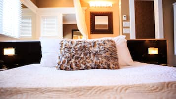 A neatly made bed with a white and leopard print pillow, a white pillow, and a white blanket.