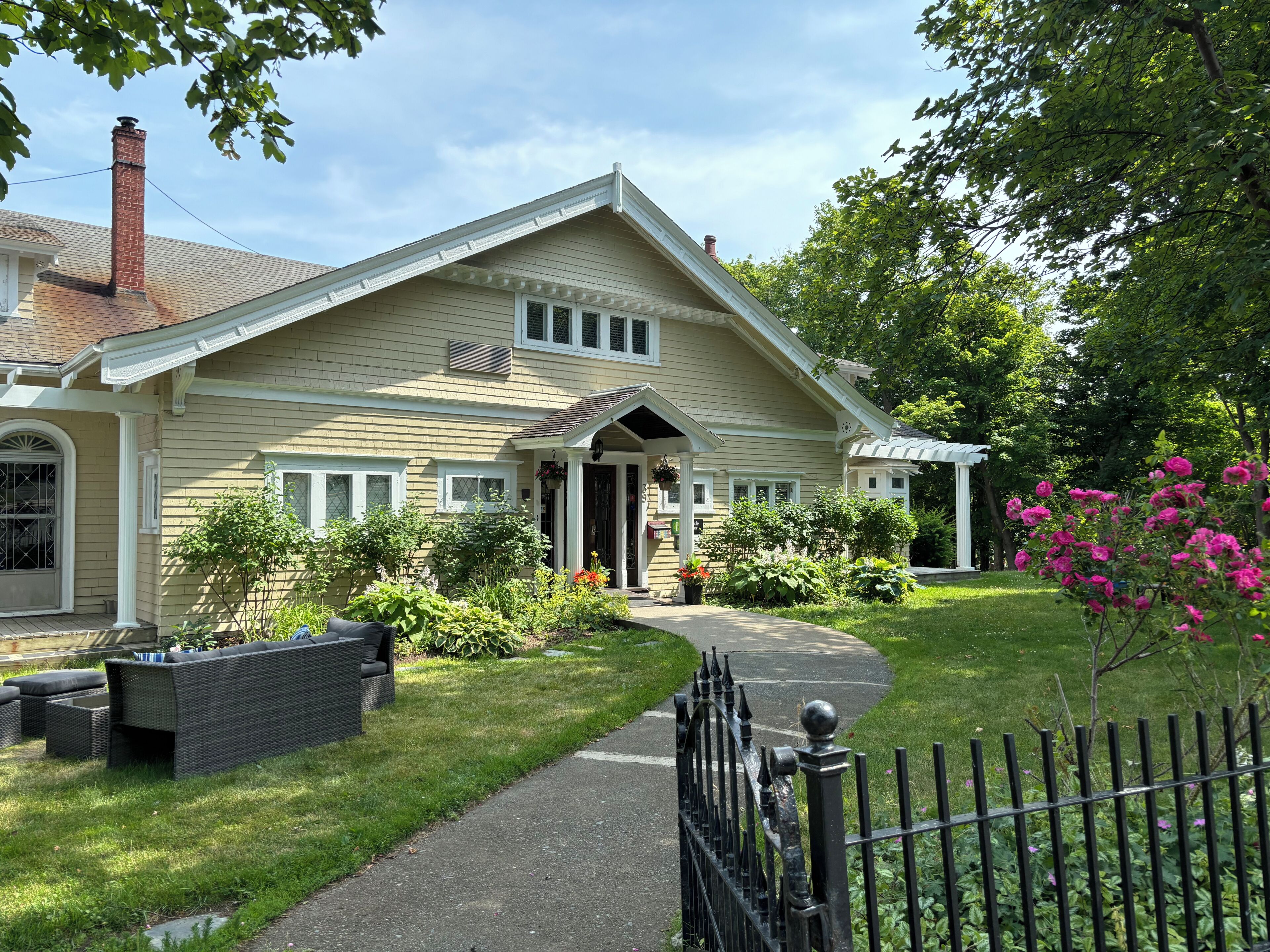 A two-story house with a front porch, a covered entryway, and a small garden with various plants and flowers.