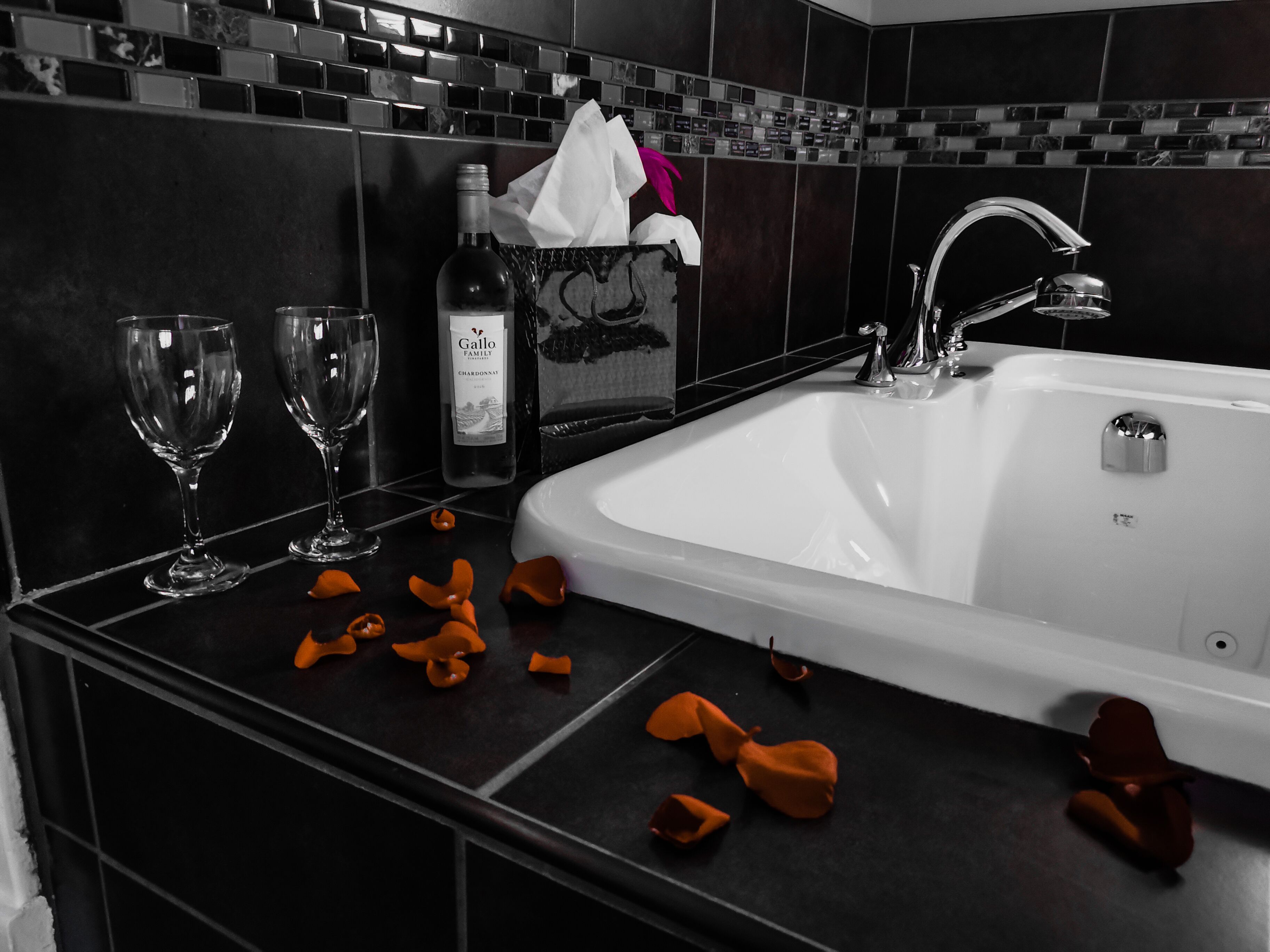 Ein modernes Badezimmer mit einem weißen Waschbecken, zwei Weingläsern und einer Weinflasche.