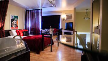 A hotel room with a bed, a desk, a TV, and a window with curtains.