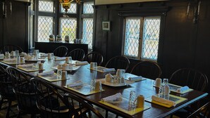 Ein Esszimmer mit einem langen Tisch, gedeckt für eine Mahlzeit, umgeben von Stühlen.