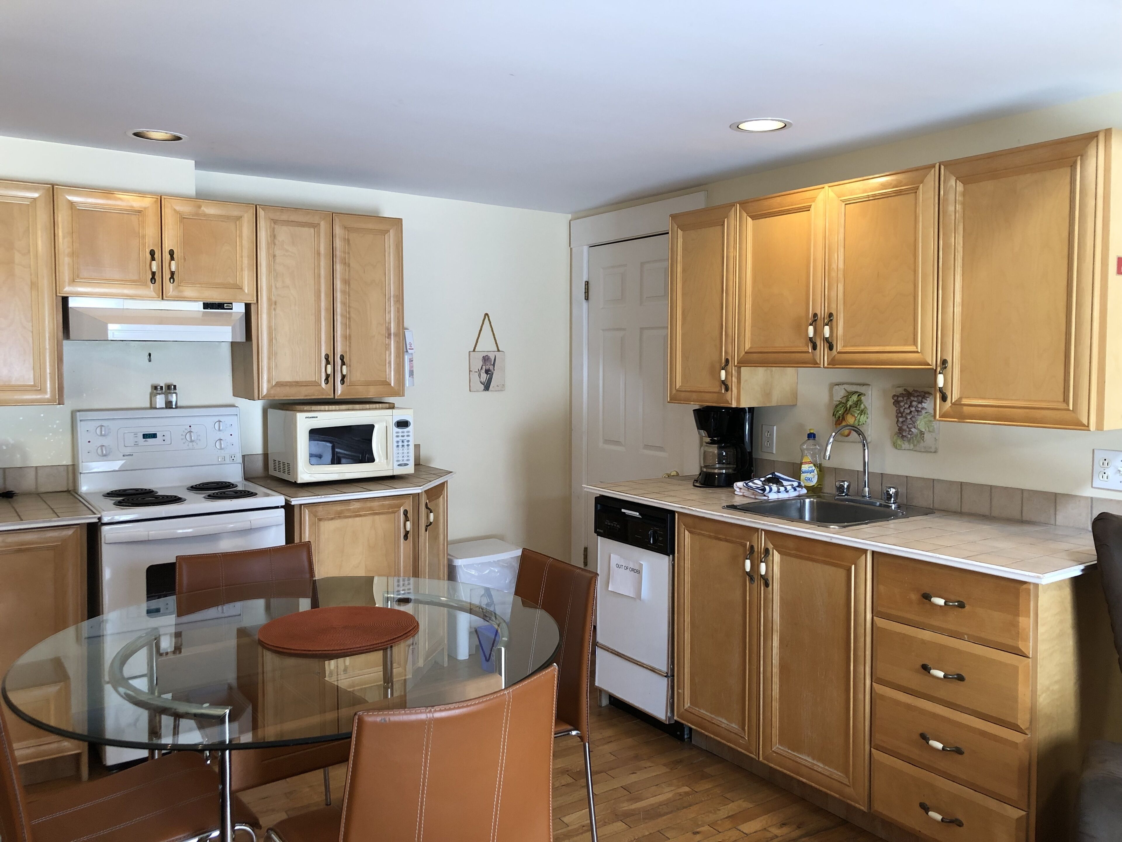 A kitchen with wooden cabinets, a glass dining table, and a built-in stove.