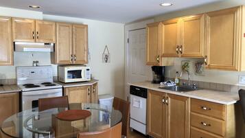 A kitchen with wooden cabinets, a glass dining table, and a built-in stove.
