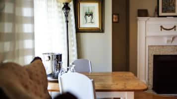 A dining area with a wooden table, white chairs, a metal pitcher, and a lamp.