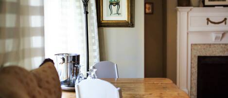 A dining area with a wooden table, white chairs, a metal pitcher, and a lamp.