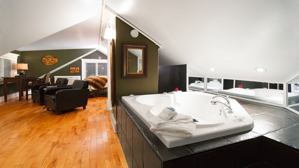 Ein modernes Badezimmer mit einer großen Badewanne, einer separaten Duschkabine und Holzboden.