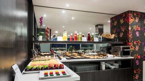 Un bufé con diversas opciones de comida y bebidas, incluyendo frutas, pasteles y refrescos.