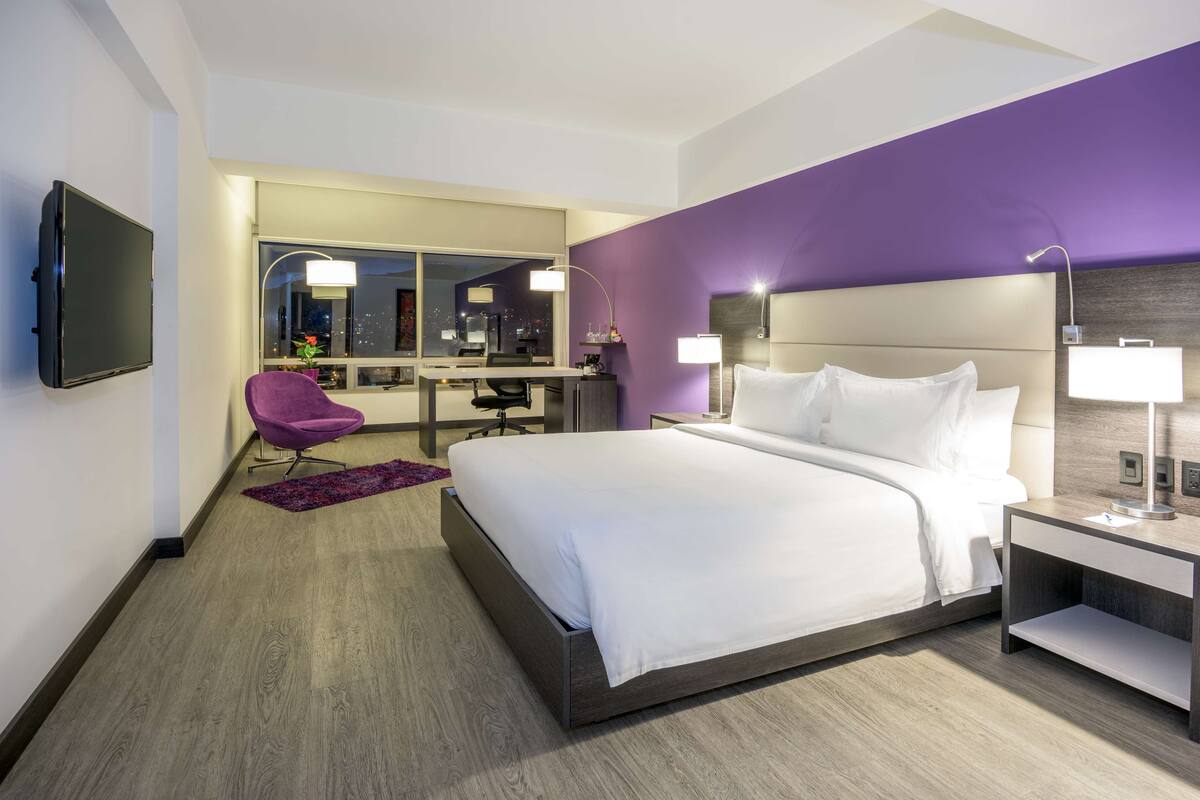 Una habitación de hotel moderna con una cama grande, un escritorio y una silla.