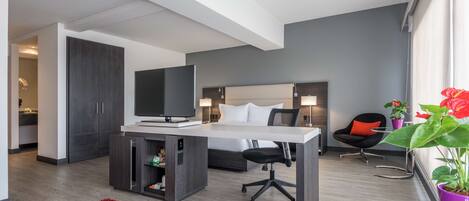 Una habitación de hotel moderna con cama, escritorio, televisor y una alfombra roja.