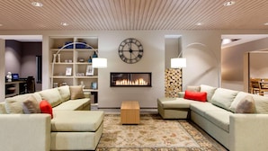A modern living room with two sofas, a fireplace, a clock, and a bookshelf. - Country Inn & Suites by Radisson, Springfield Southeast (Springfield)