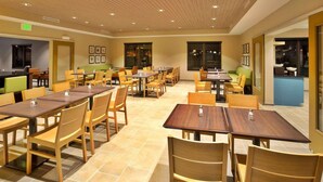 A spacious dining area with multiple tables and chairs, a kitchen area visible through an open door, and an exit sign on the wall. - Country Inn & Suites by Radisson, Springfield Southeast (Springfield)