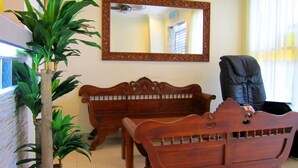 A room with two wooden sofas, a black chair, and a large mirror on the wall. - Sun Inns Hotel Equine Seri Kembangan (Seri Kembangan)