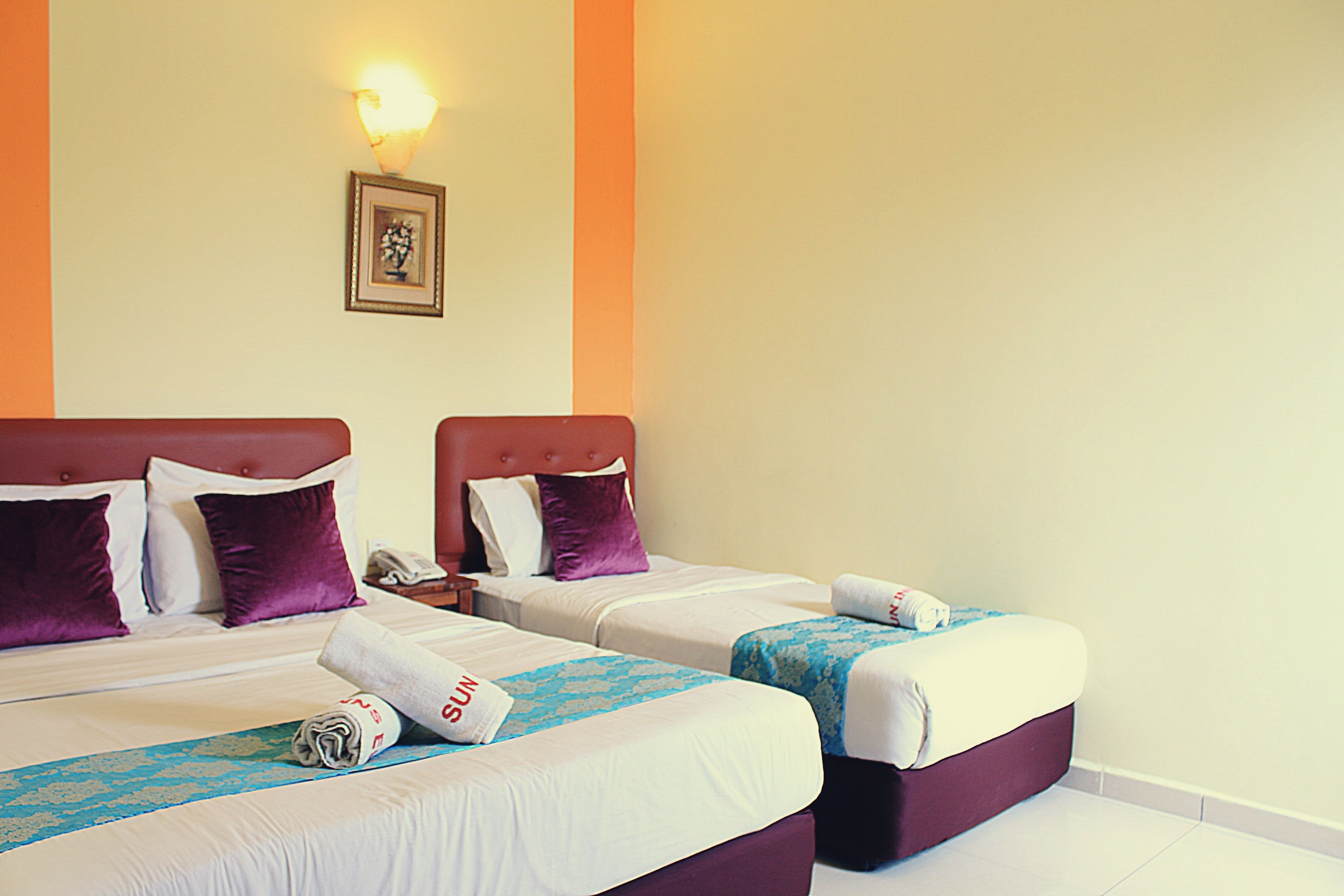 A hotel room with two beds, each with a headboard, pillows, and a blanket.