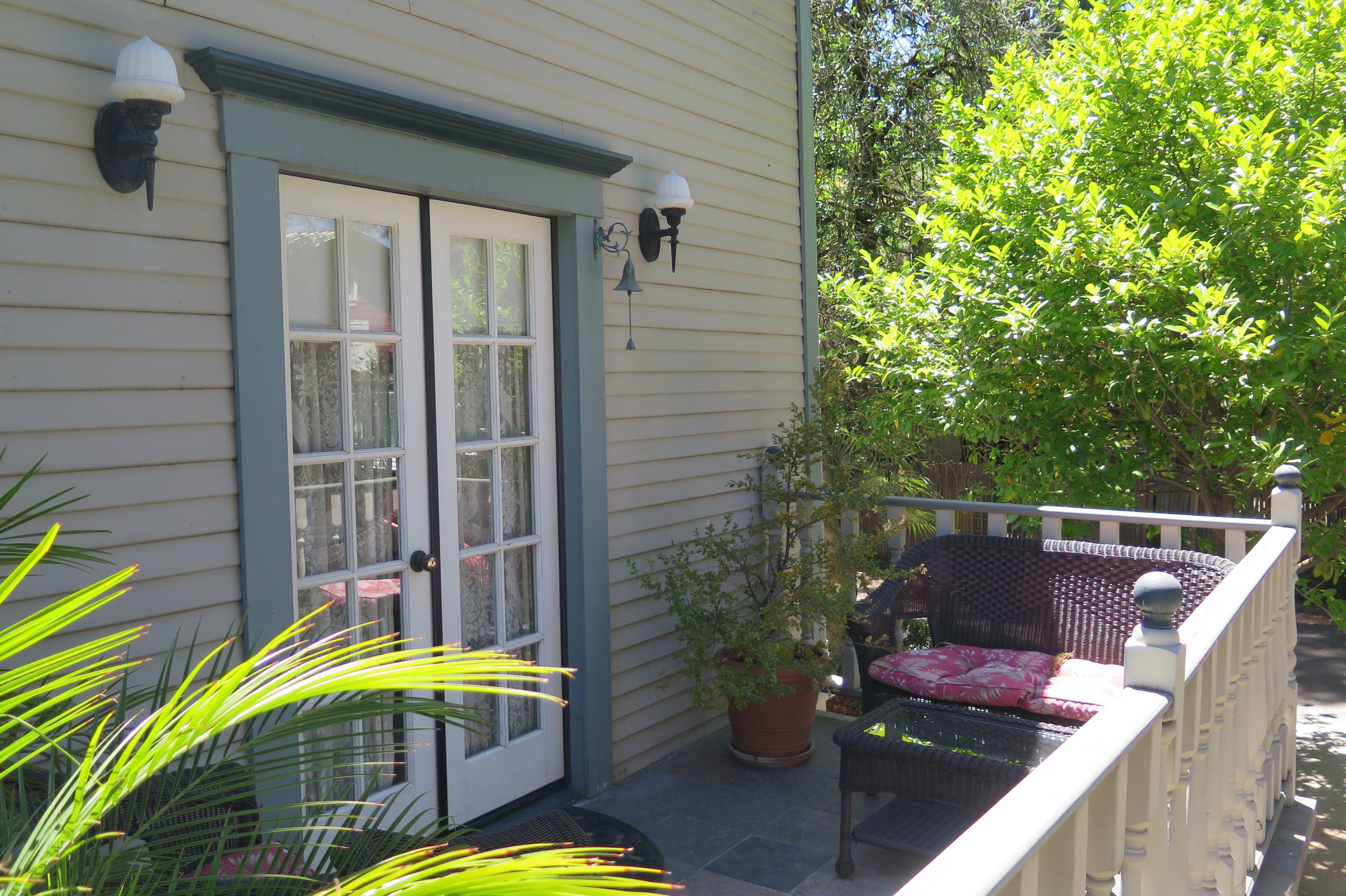 A porch with a wicker chair and a potted plant.