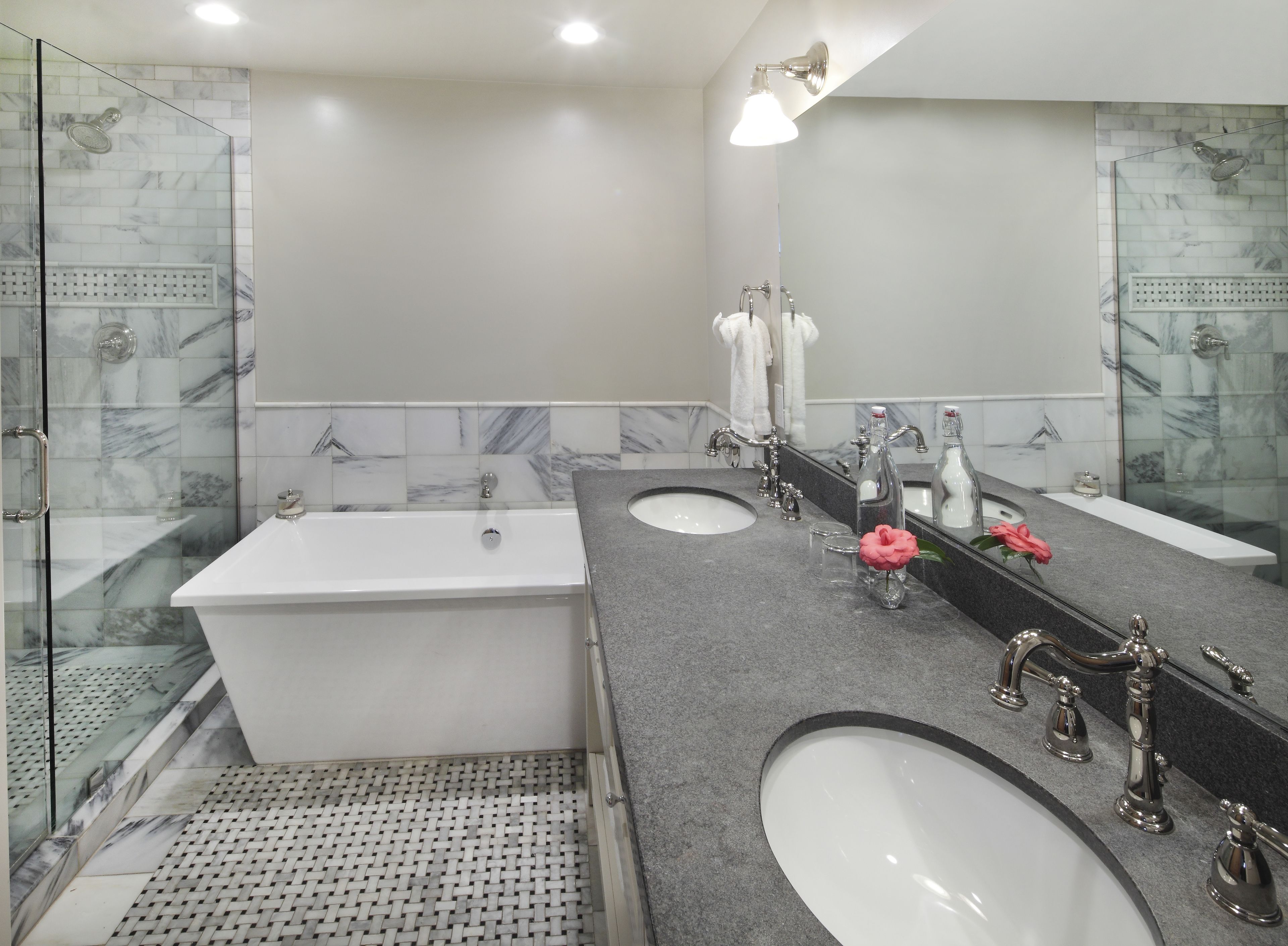 Un baño moderno con bañera, dos lavabos, ducha y un espejo grande.