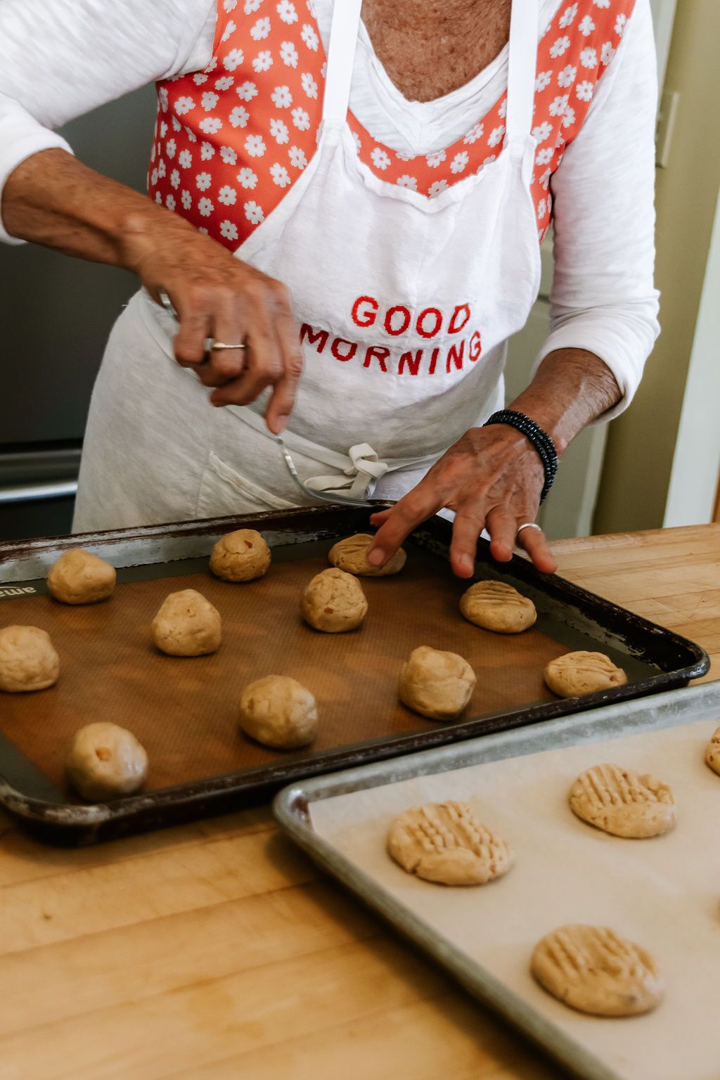 Uma pessoa na cozinha preparando biscoitos em uma assadeira.