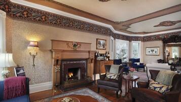A traditional living room with a fireplace, patterned wallpaper, and classic furniture.