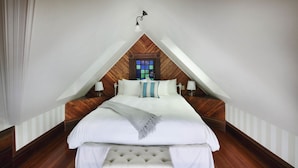 A bedroom with a wooden ceiling, a large bed with white bedding, a bench at the foot of the bed, and a window with a view. - Grape Leaf Inn (Healdsburg)