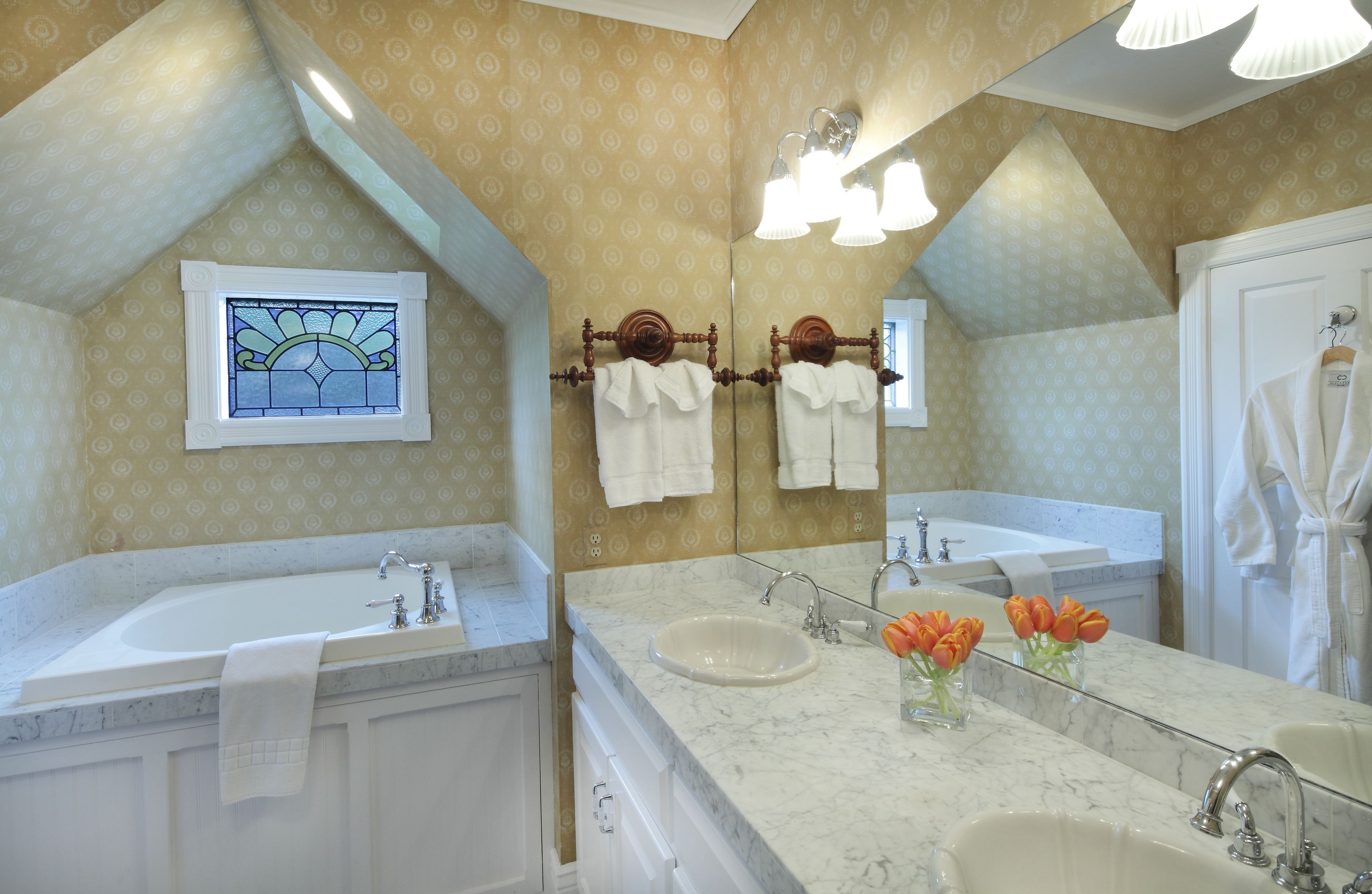 Un baño con dos lavamanos, un espejo grande y una ventana con vitrales.