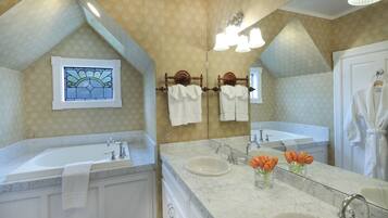 Un baño con dos lavamanos, un espejo grande y una ventana con vitrales.