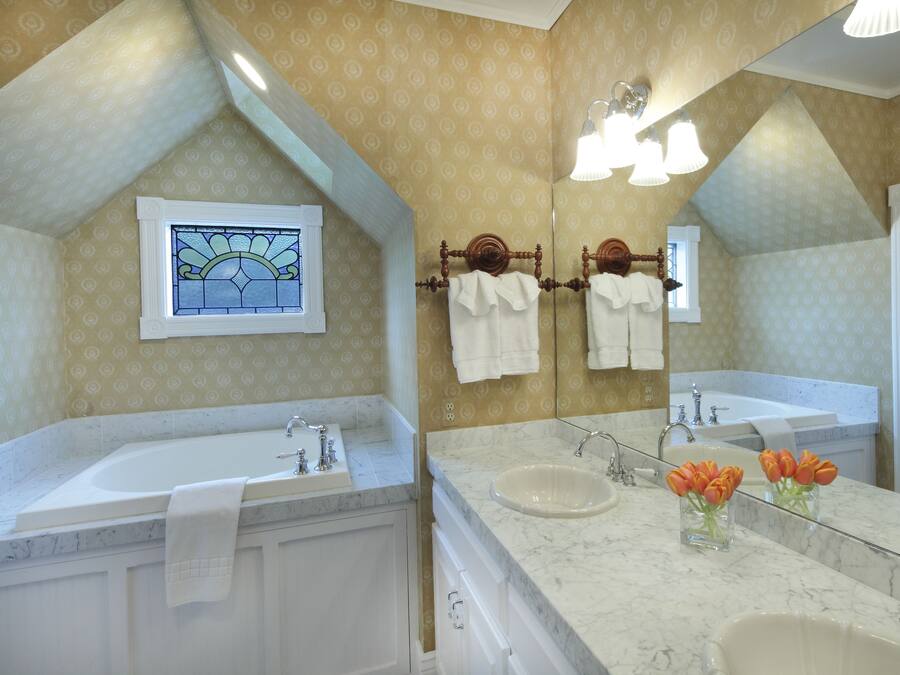 Un baño con dos lavamanos, un espejo grande y una ventana con vitrales.